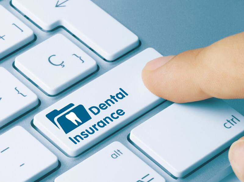 index finger pressing a keyboard button that reads 'Dental Insurance'